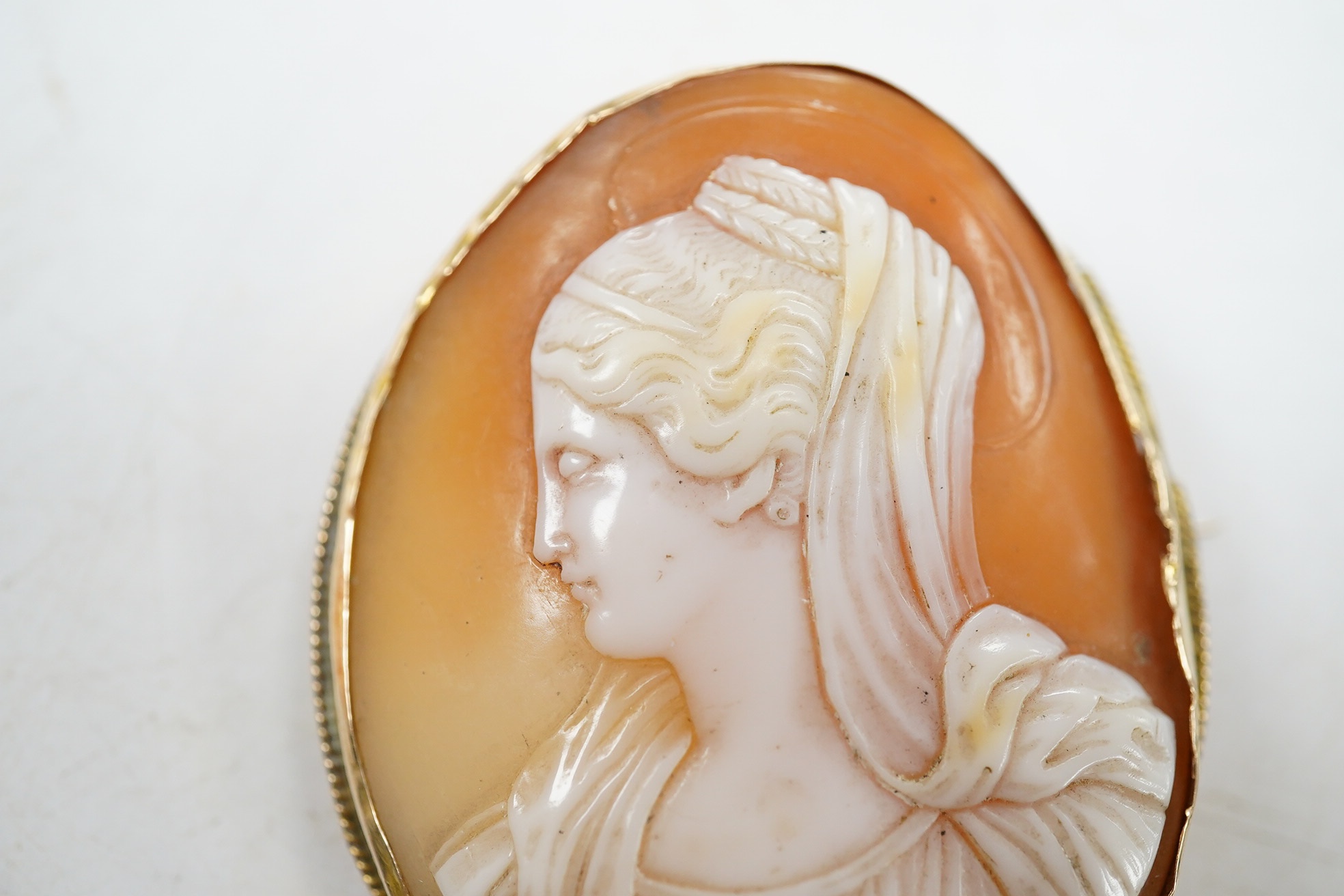 A yellow metal mounted oval cameo shell brooch, carved with the bust of a lady to dexter, 45mm. Condition - fair